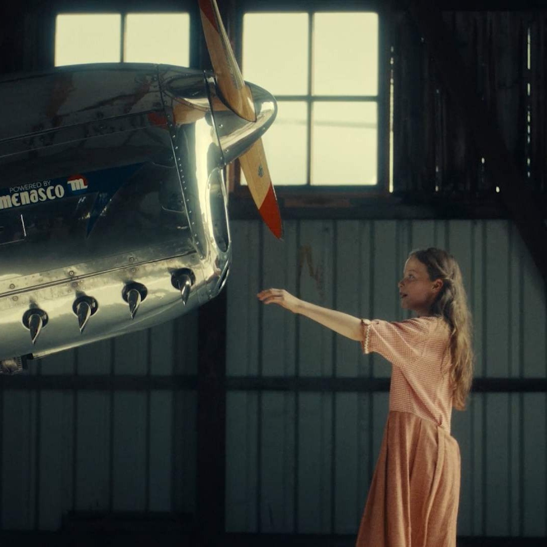 Un niña tocando un avión antiguo