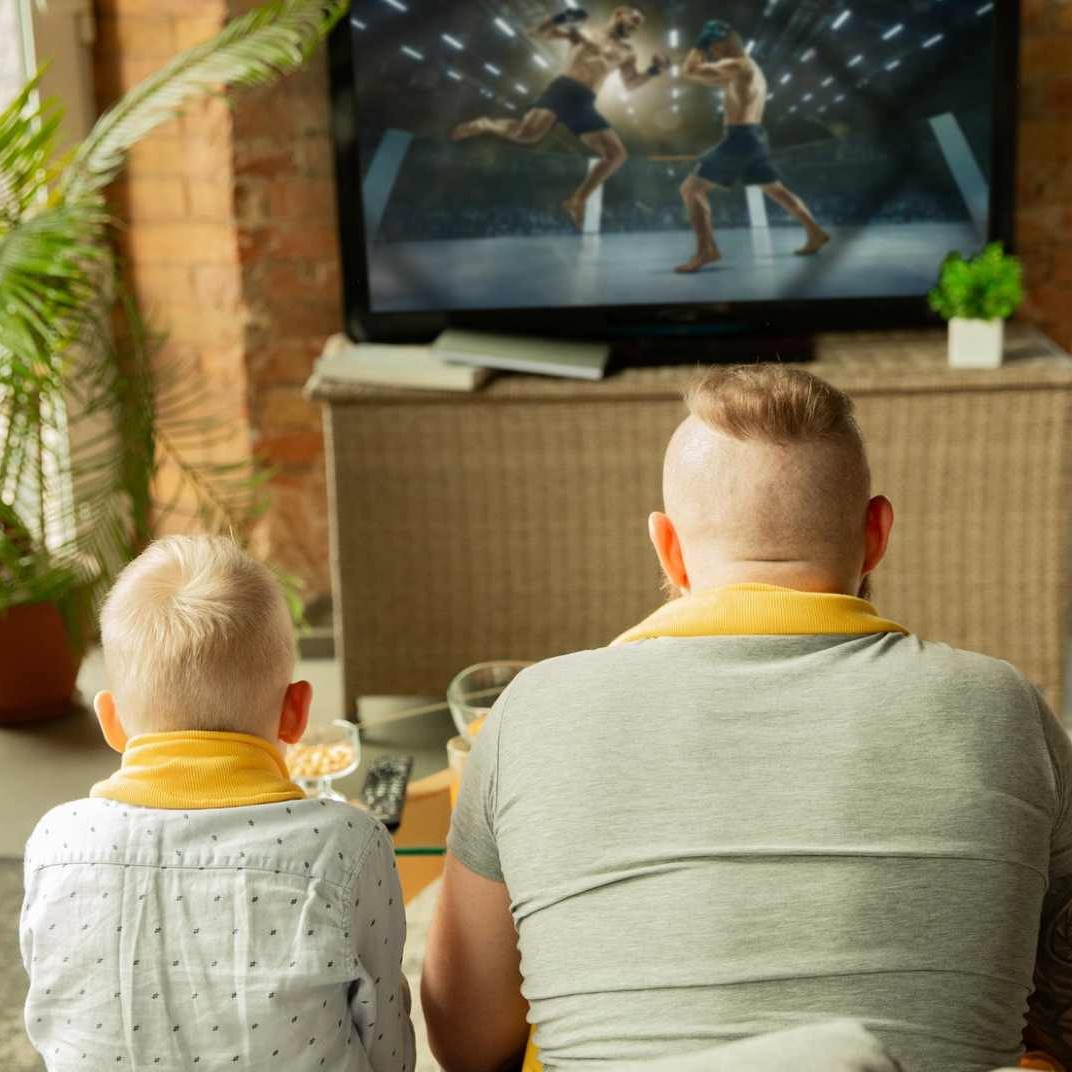 Un padre y un hijo viendo un combate de boxeo en la televisión