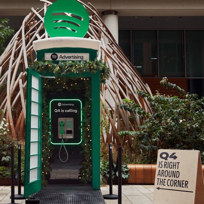 cabina de telefono decorada con luces de navidad y la identidad corporativa de spotify