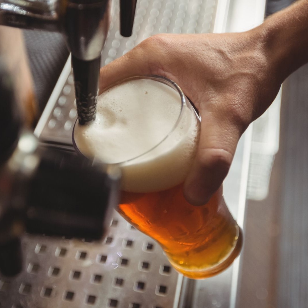 Hombre llenando un vaso de cerveza de grifo