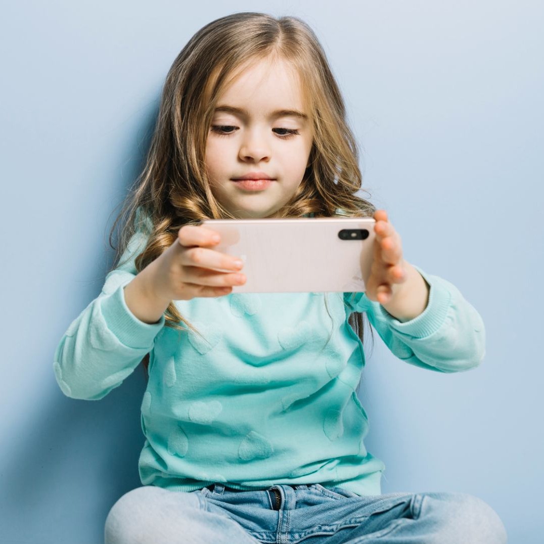 Niña mirando un teléfono móvil