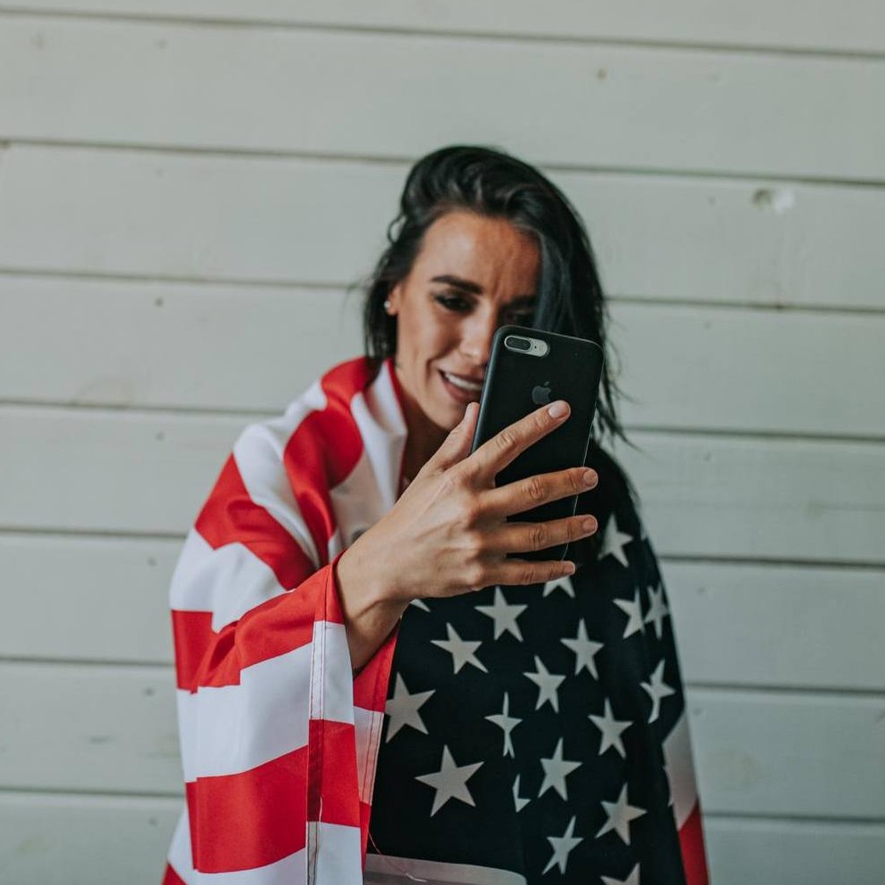 Chica con la bandera estadounidense se graba con el móvil