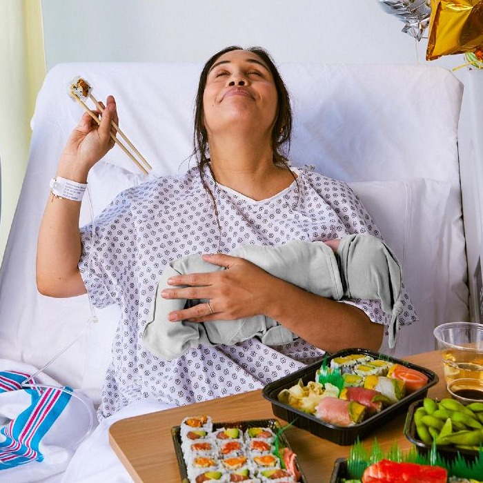 una madre recién parida comiendo sushi en la cama del hospital