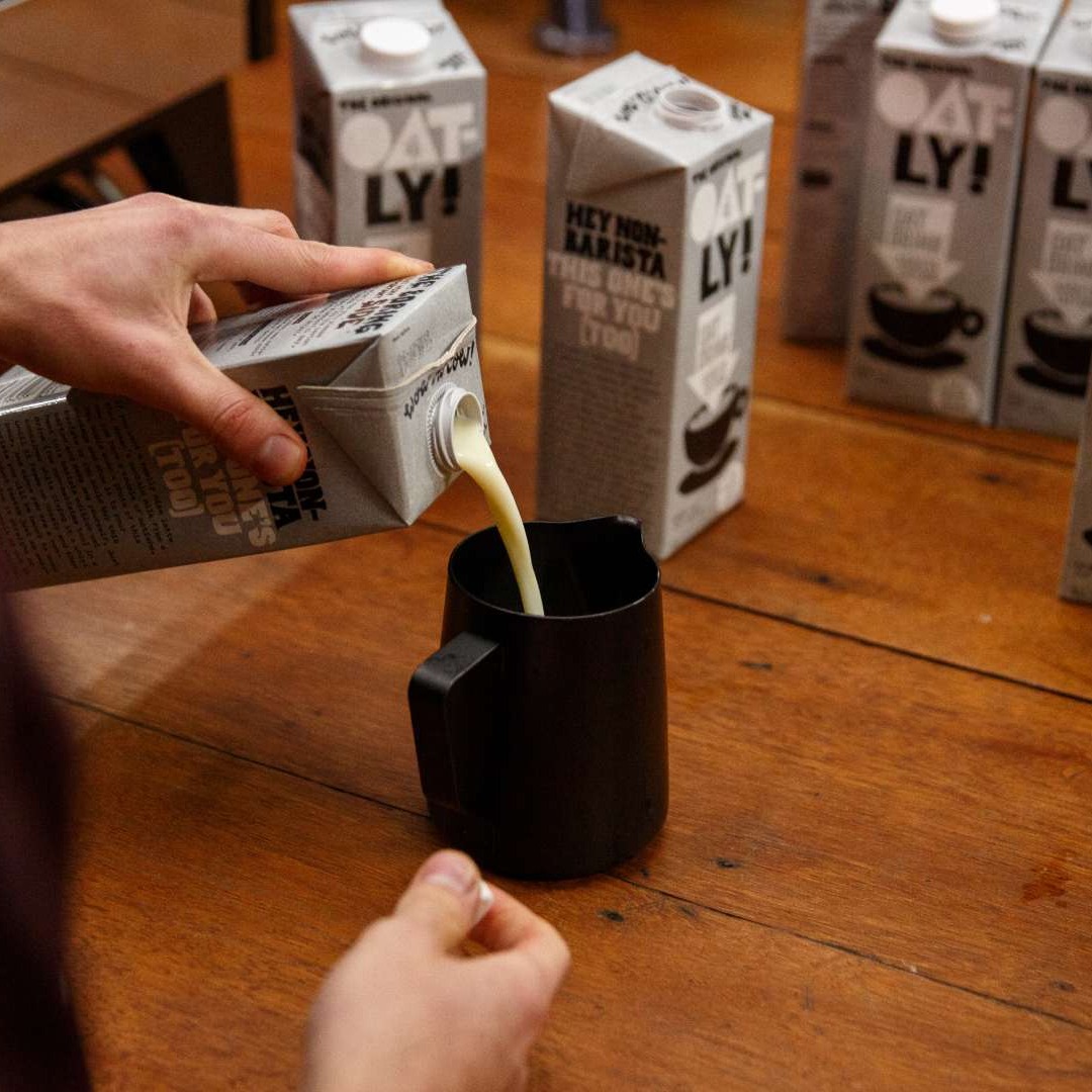 Un hombre sirve leche vegetal de la marca Oatly