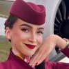 Una azafata vestida con el uniforme de Qatar Airways posando con la mano junto a la mejilla