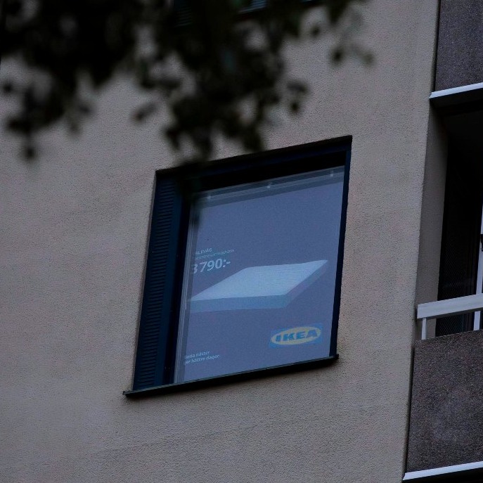 una ventana de un edificio con una persiana que muestra un anuncio de un colchón de ikea