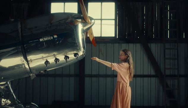 Un niña tocando un avión antiguo