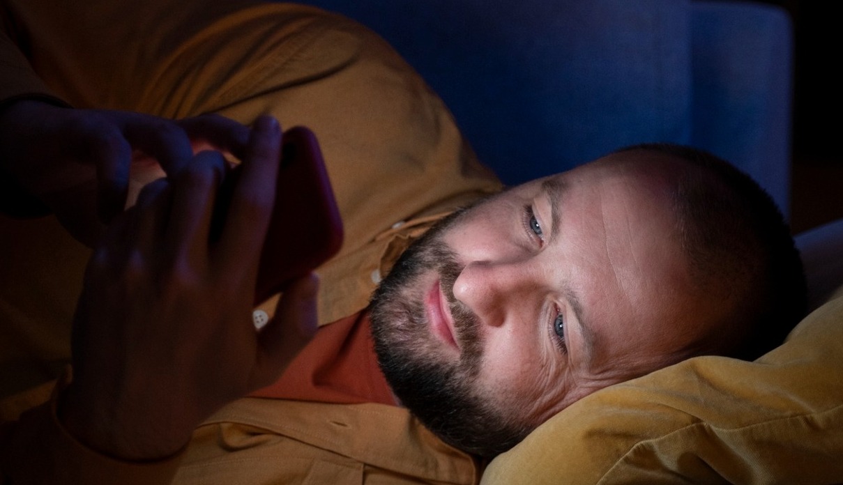 in hombre mirando el movil en la cama por la noche