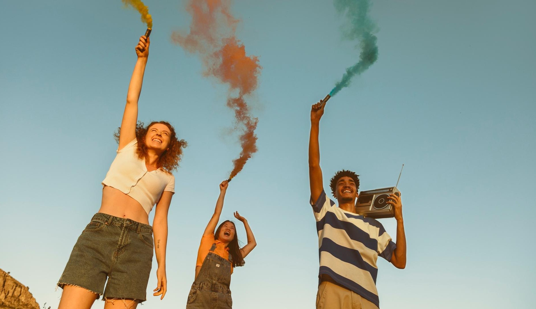 Tres jóvenes sostiene bengalas de colores