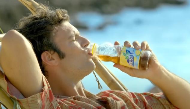 un chico bebiendo nestea en la hamaca de la playa