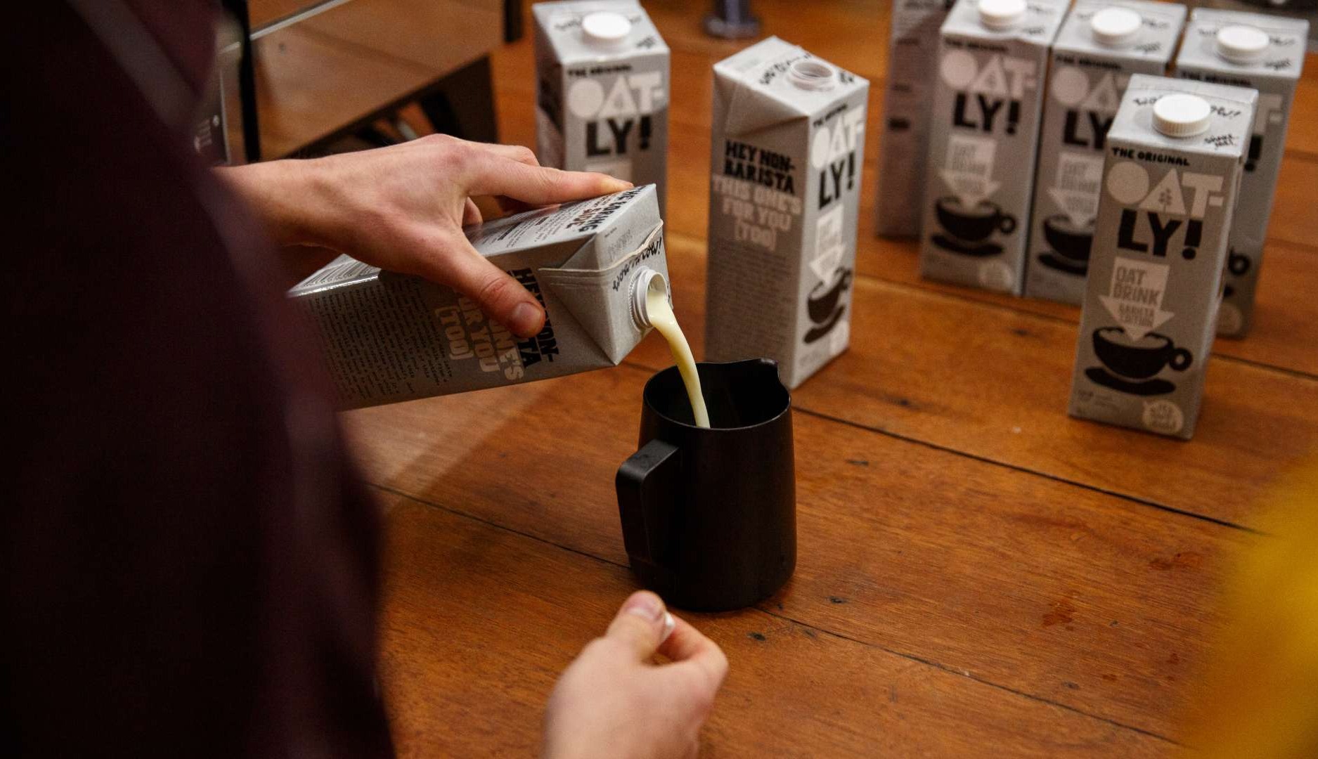 Un hombre sirve leche vegetal de la marca Oatly