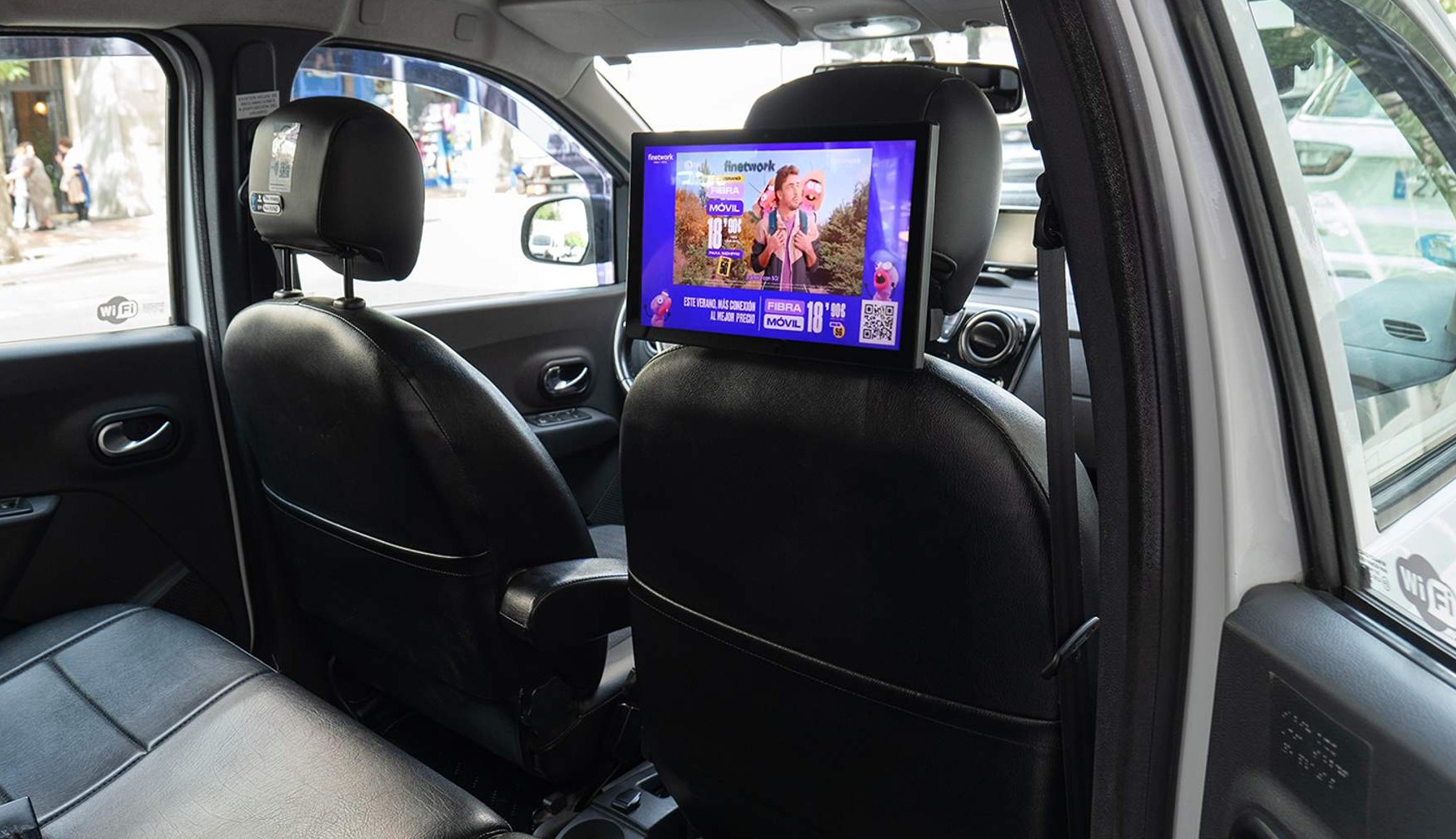 una pantalla en el interior de un taxi, sujeta en el asiento del copiloto