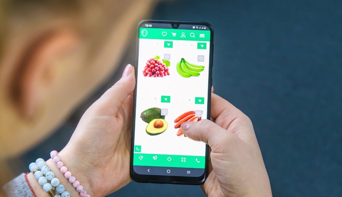 una mujer comprando zanahorias desde el móvil en un supermercado online