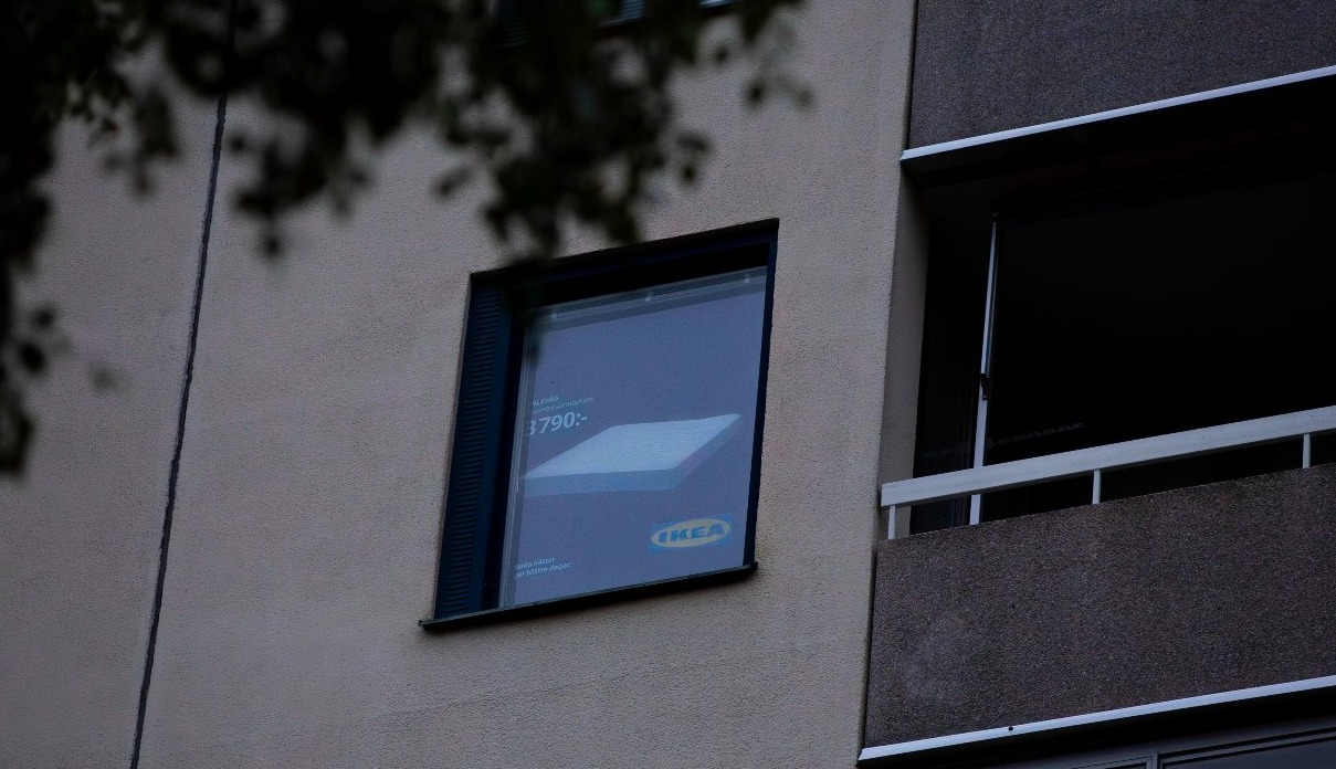 una ventana de un edificio con una persiana que muestra un anuncio de un colchón de ikea