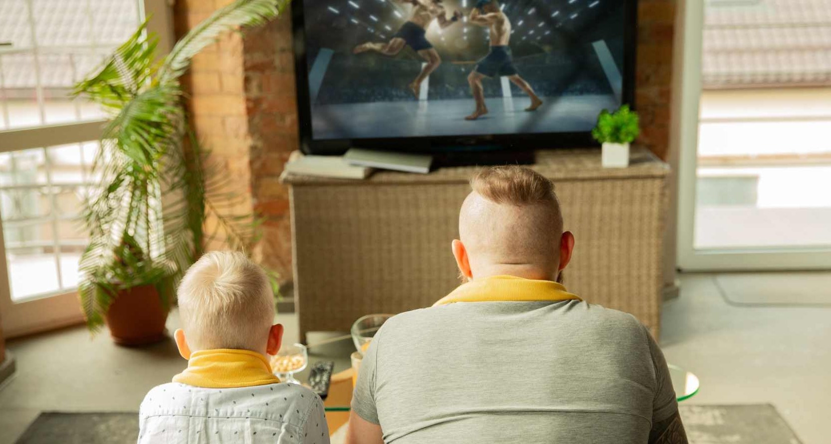 Un padre y un hijo viendo un combate de boxeo en la televisión