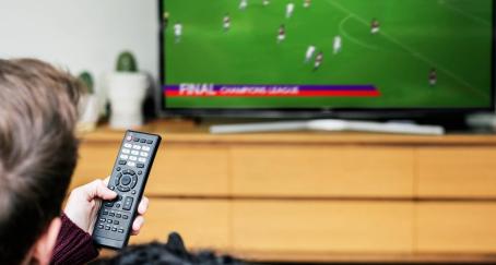 Hombre con mando a distancia en la mano viendo fútbol en televisión