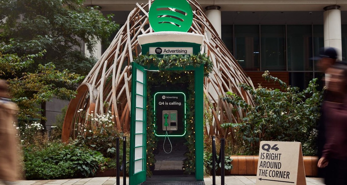 cabina de telefono decorada con luces de navidad y la identidad corporativa de spotify