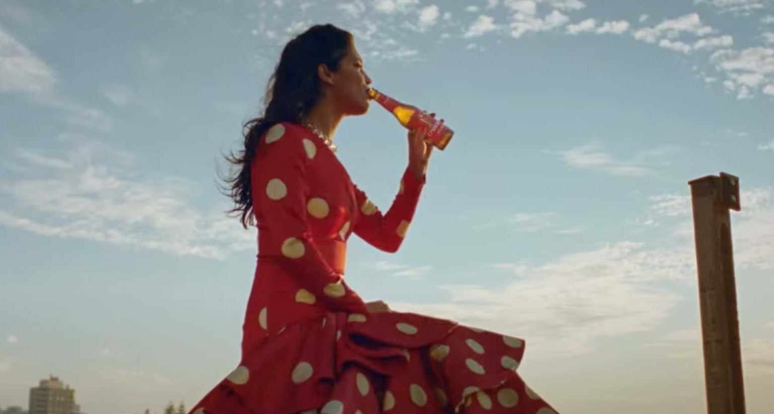 Mujer vestida de flamenca bebe botellín de Cruzcampo