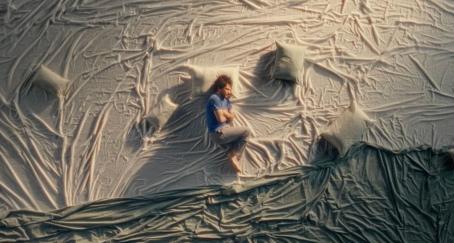 La culpa de provocar un accidente es el insight de la campaña “Morir o perder la vida” de la DGT Plano cenital de un hombre acurrucado sobre telas y almohadas