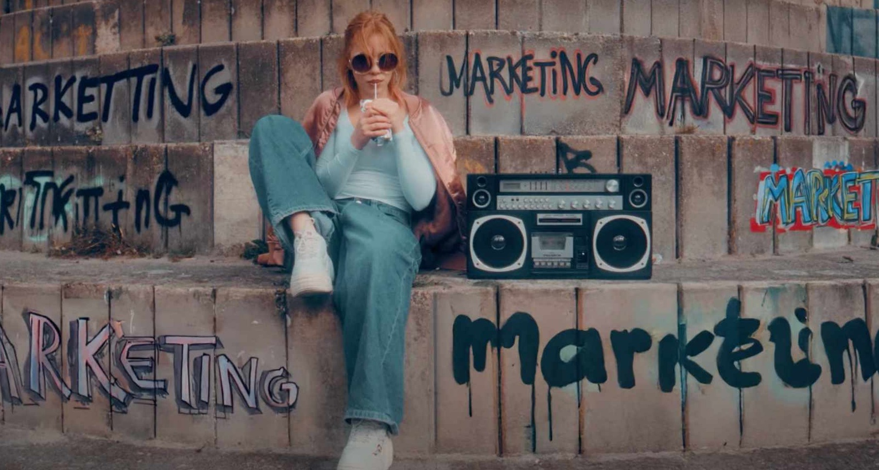 Una chica sentada junto a una radio y rodeada de grafitis con la palabra marketing