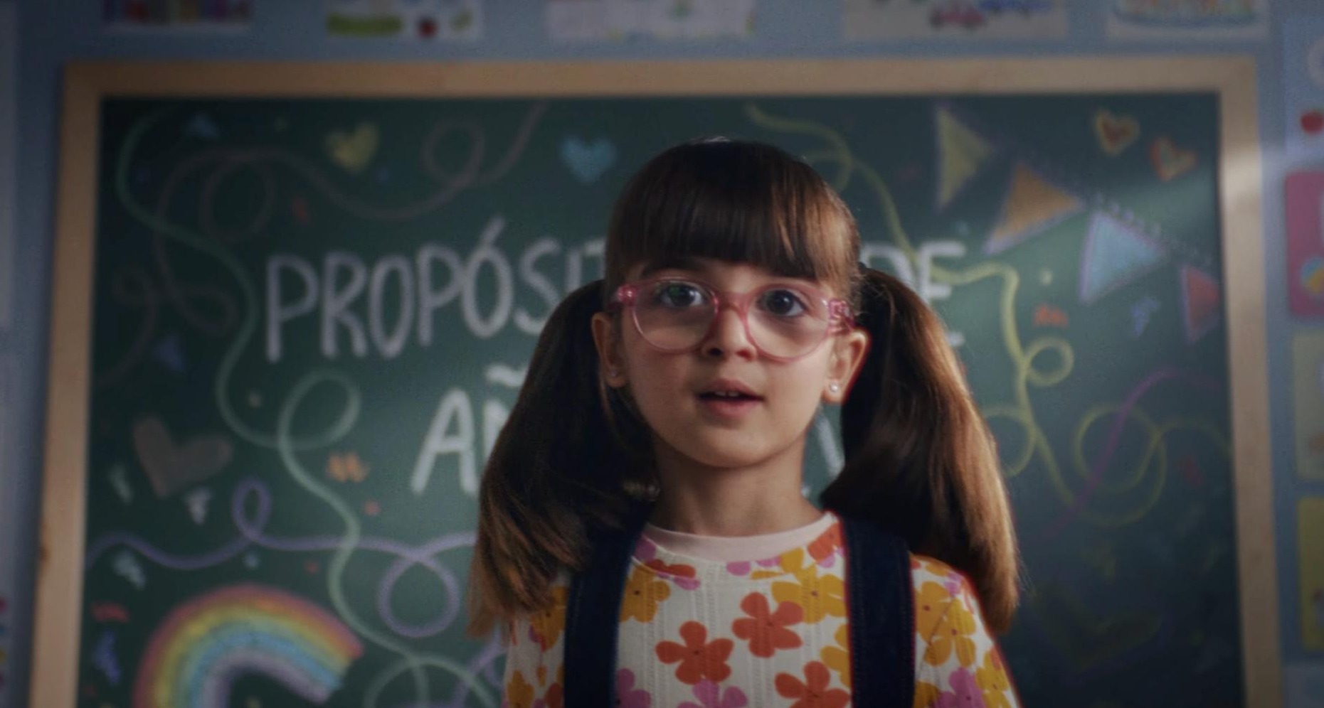 Niña con gafas delante de un pizarra