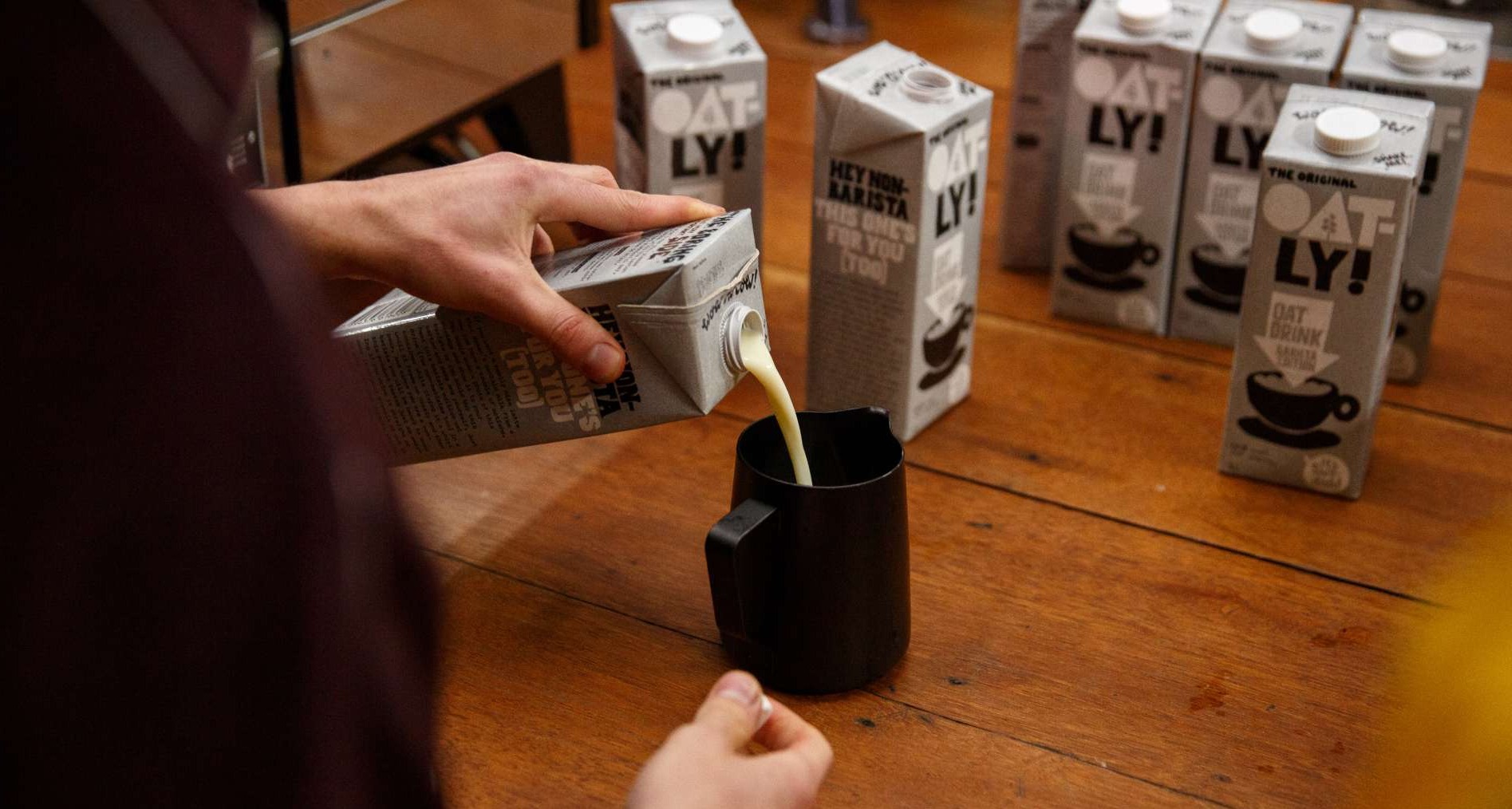 Un hombre sirve leche vegetal de la marca Oatly