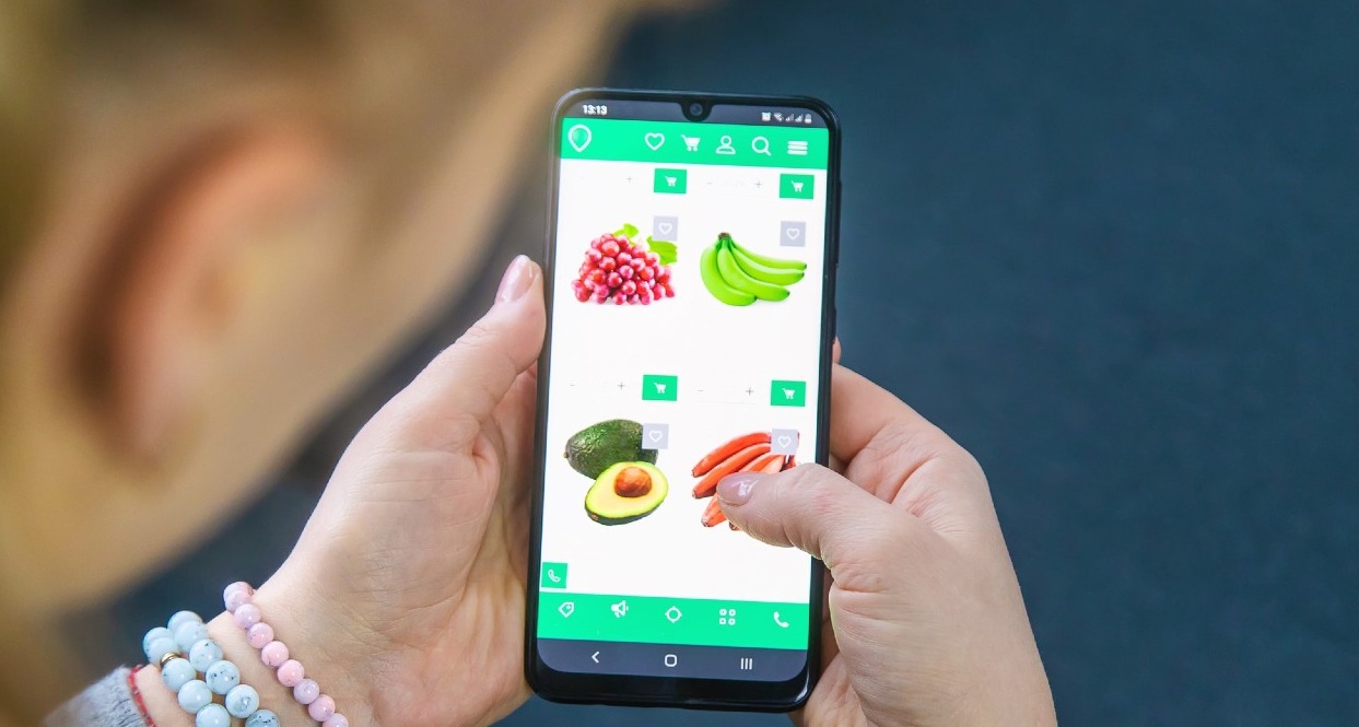 una mujer comprando zanahorias desde el móvil en un supermercado online