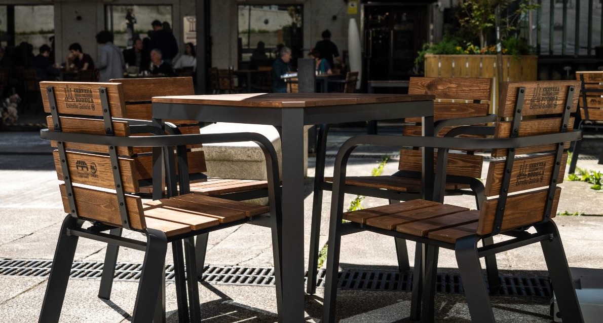 conjunto de sillas y mesa en una terraza de un bar con madera reciclada