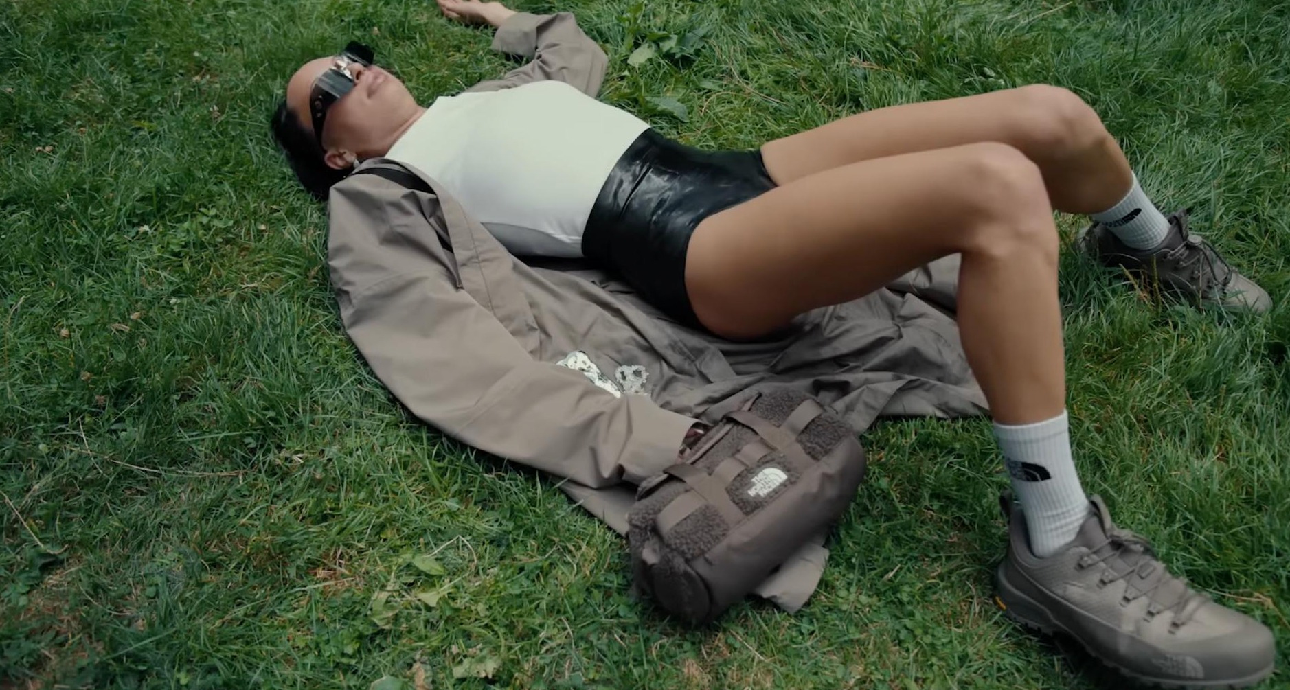 “Sal a tocar hierba”: la invitación de The North Face a la generación Z a conectar con la naturaleza Chica vestida con ropa de The North Face tumbada sobre hierba