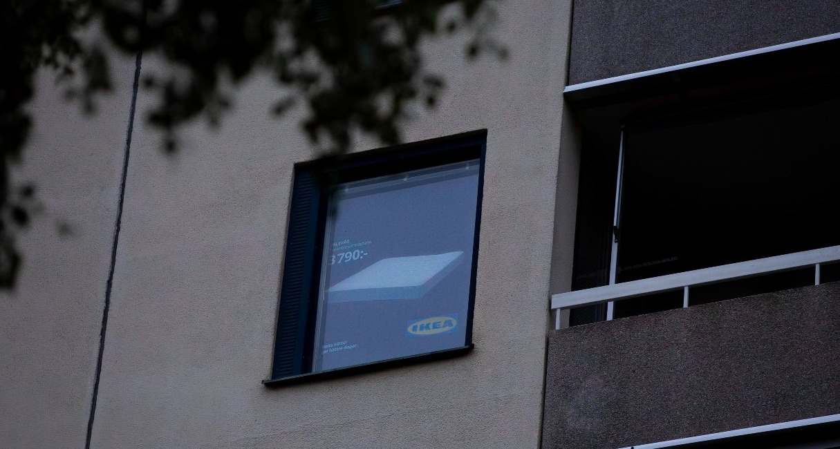 una ventana de un edificio con una persiana que muestra un anuncio de un colchón de ikea