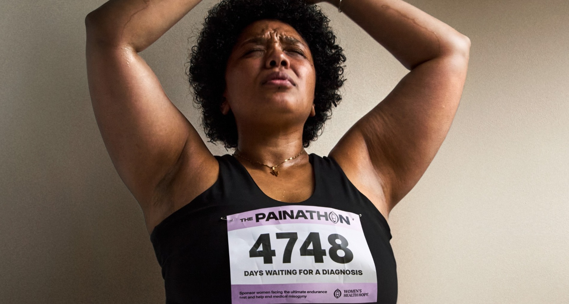 Esta iniciativa convierte los días de espera para recibir atención ginecológica en una maratón benéfica Mujer con expresión de dolor levantando los brazos con los ojos cerrados, y un dorsal de la campaña Painathon en la camiseta.